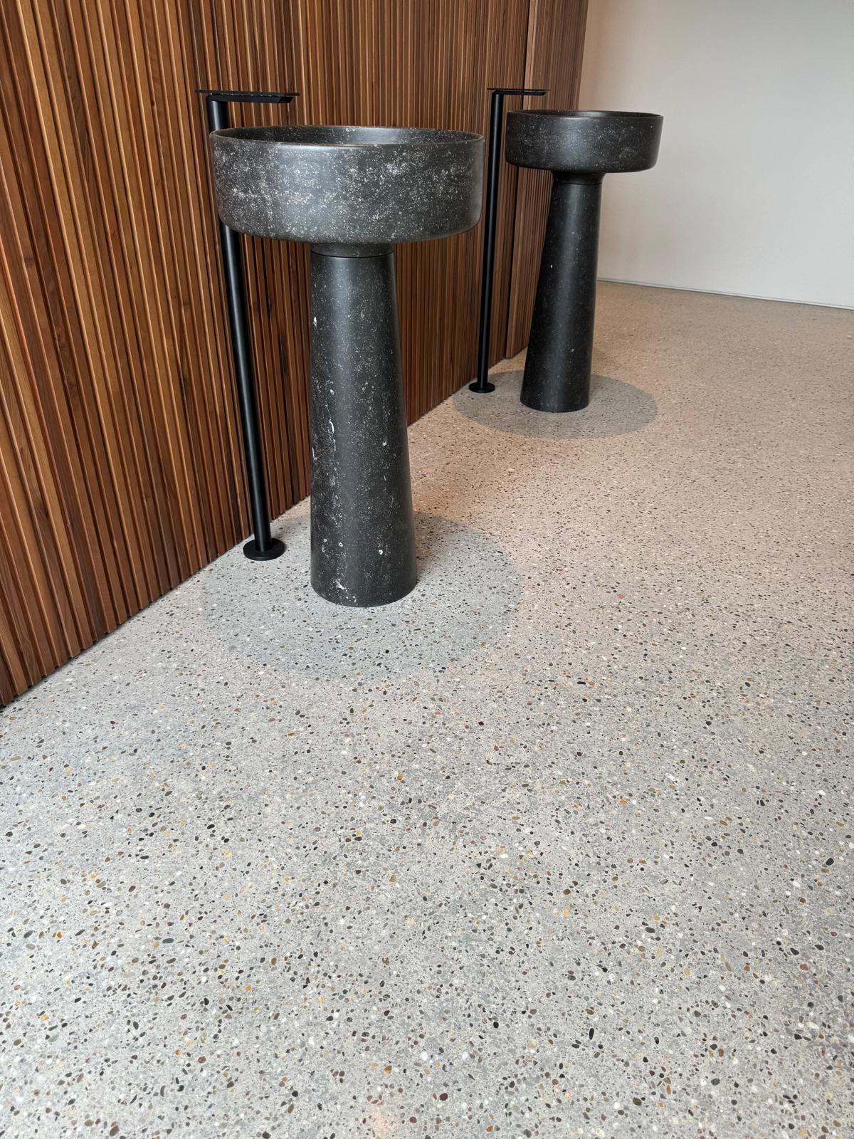 Fertiger Terrazzo-Raum mit skulpturalen Waschbecken und warmer Holzverkleidung